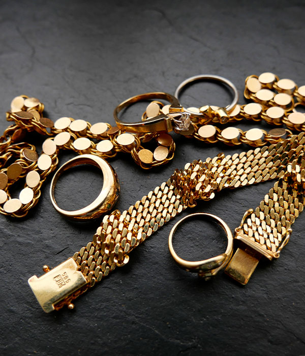 Gold jewellery with bracelet, necklace and rings on slate plate